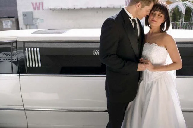 Bride and Groom Standing Together in Front of a Stretch Limousine 